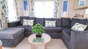 A living room with a sectional sofa, a small round table, and a potted plant.