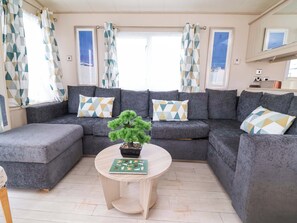 Ein Wohnzimmer mit Ecksofa, einem kleinen runden Tisch und einer Topfpflanze.