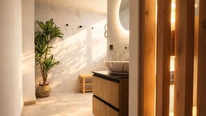 Un baño moderno con pared de mármol, un mueble de madera y una planta en maceta.