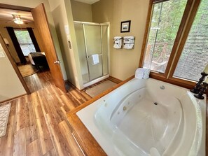 Ein Badezimmer mit einer großen Badewanne, einer Dusche und Holzboden.
