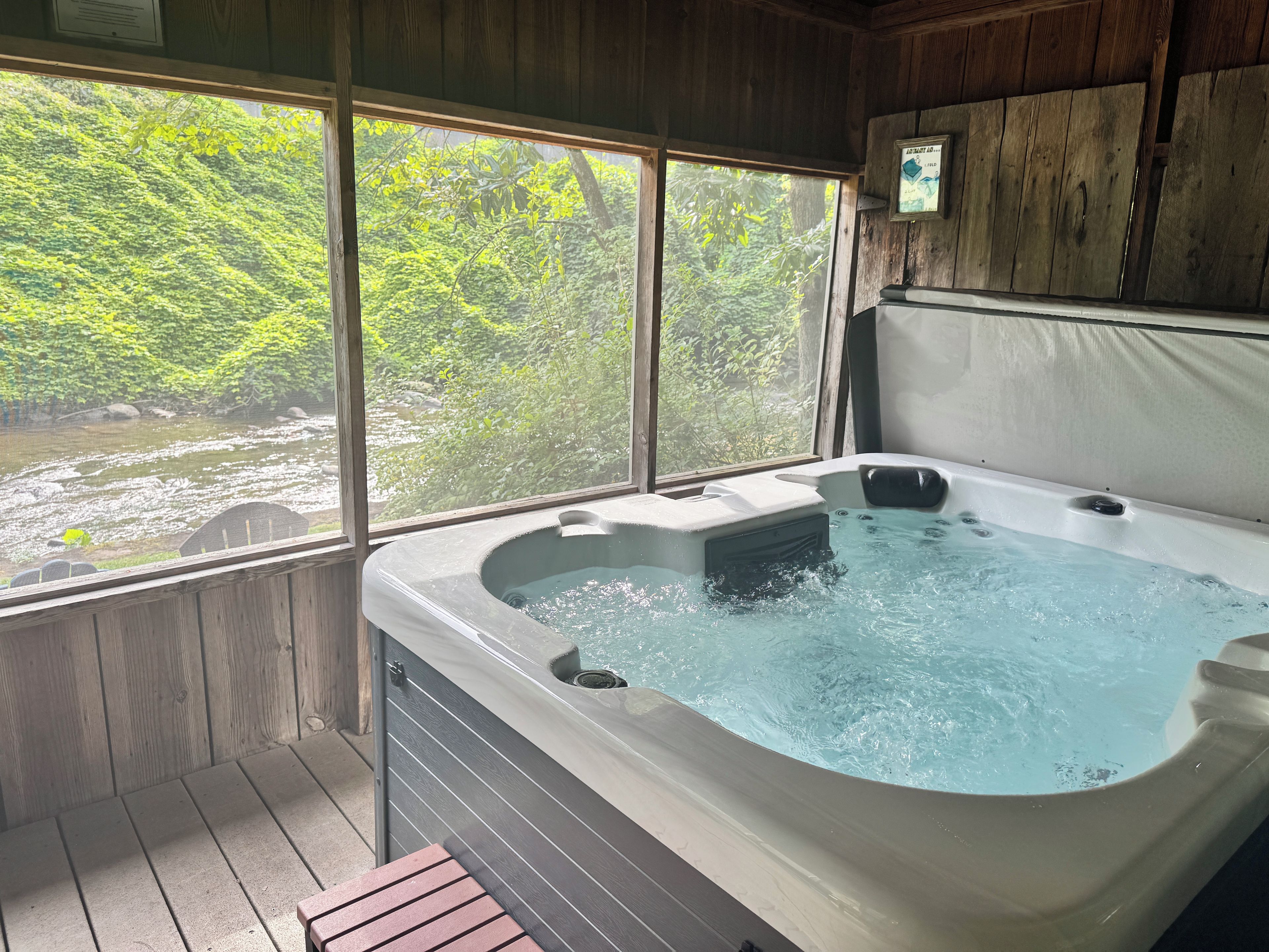 Un bain à remous avec vue sur une rivière et une forêt, grâce à de grandes fenêtres.