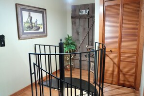 A staircase with a metal railing, a wooden door with a 'WELCOME' sign, and a framed picture on the wall. - Historic Two-story Riverside Cabin w/Hot Tub in Gatinburg (Gatlinburg)
