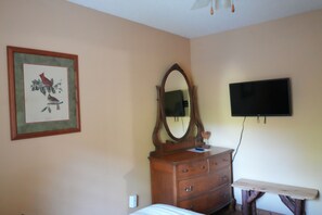 A bedroom with a bed, dresser, mirror, and a flat-screen TV mounted on the wall. - Historic Two-story Riverside Cabin w/Hot Tub in Gatinburg (Gatlinburg)