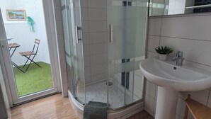 A modern bathroom with a glass shower enclosure, a white sink, and a view of a garden through the glass door. - Old fisherman's cottage completely renovated (Étel)
