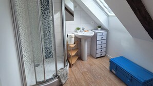 A modern bathroom with a glass shower, a white sink, and a wooden floor. - Old fisherman's cottage completely renovated (Étel)