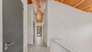A hallway with a wooden ceiling, a grey door, and a view of a green outdoor area. - NEW 4BR Villa With 2 Pools at Blue Bay (Sint Michiel)