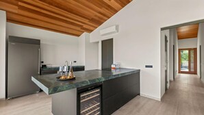 A modern kitchen with a marble countertop, built-in wine cooler, and a wooden ceiling. - NEW 4BR Villa With 2 Pools at Blue Bay (Sint Michiel)