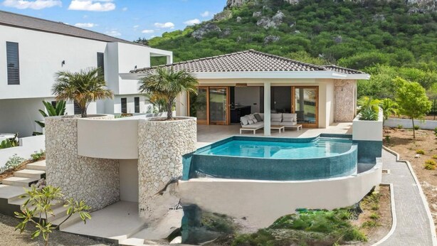 A modern house with a swimming pool, stone walls, and a patio area. - NEW 4BR Villa With 2 Pools at Blue Bay (Sint Michiel)