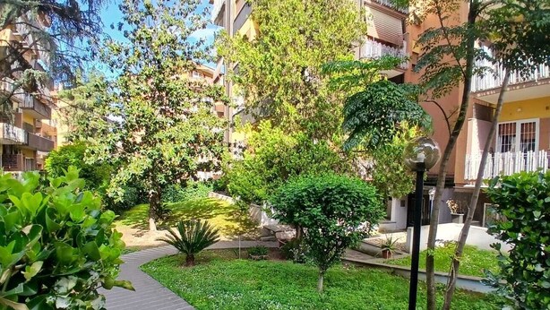 A pathway surrounded by greenery, leading to a building with balconies. - Cozy apartment in Talenti - Well connected and quiet" (Roma)