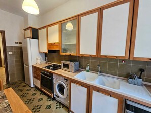 A compact kitchen with a gas stove, microwave, oven, washing machine, and a sink. - Cozy apartment in Talenti - Well connected and quiet" (Roma)