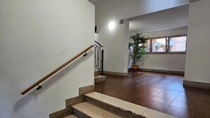 A staircase with a handrail, a potted plant, and a window with a view of buildings. - Cozy apartment in Talenti - Well connected and quiet" (Roma)