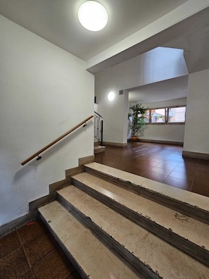 A staircase with a handrail, a potted plant, and a window with a view of buildings. - Cozy apartment in Talenti - Well connected and quiet" (Roma)