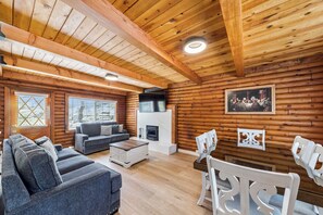 Ein rustikales Blockhaus mit Kamin, Holzwänden, einer Couch und einem Essbereich.