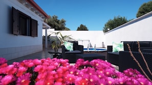 A patio area with outdoor furniture, a pool, and a white building with shutters. - Villa with Private Pool in Sardinia - Relax & Privacy (Quartu Sant'Elena)