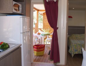 A compact kitchen with a refrigerator, a dining area with a table and chairs, and a bedroom with a bed. - Beach Escape With Pool Access (Hyères)