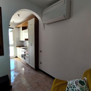 A kitchen with white cabinets, a microwave, and a tiled floor. - APTBellavista (Corniglia)
