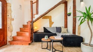 A cozy interior with a wooden staircase, a black sofa, a small round table, and a potted plant. - Maisonette in center of Chania with roofgarden! (Chania)