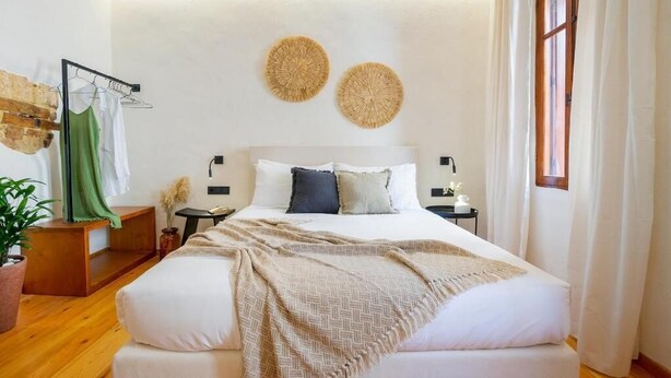A bedroom with a large bed, wooden floor, a wall-mounted shelf, and a window with curtains. - Maisonette in center of Chania with roofgarden! (Chania)