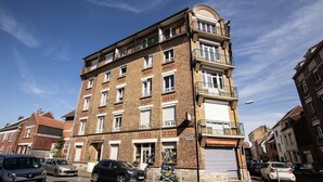 En bygning med flere etager, facade i mursten, flere balkoner og en indgang i stueplan.