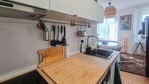 Et moderne køkken med træbordplader, hængende redskaber, en indbygget vask og udsigt til spiseområdet.