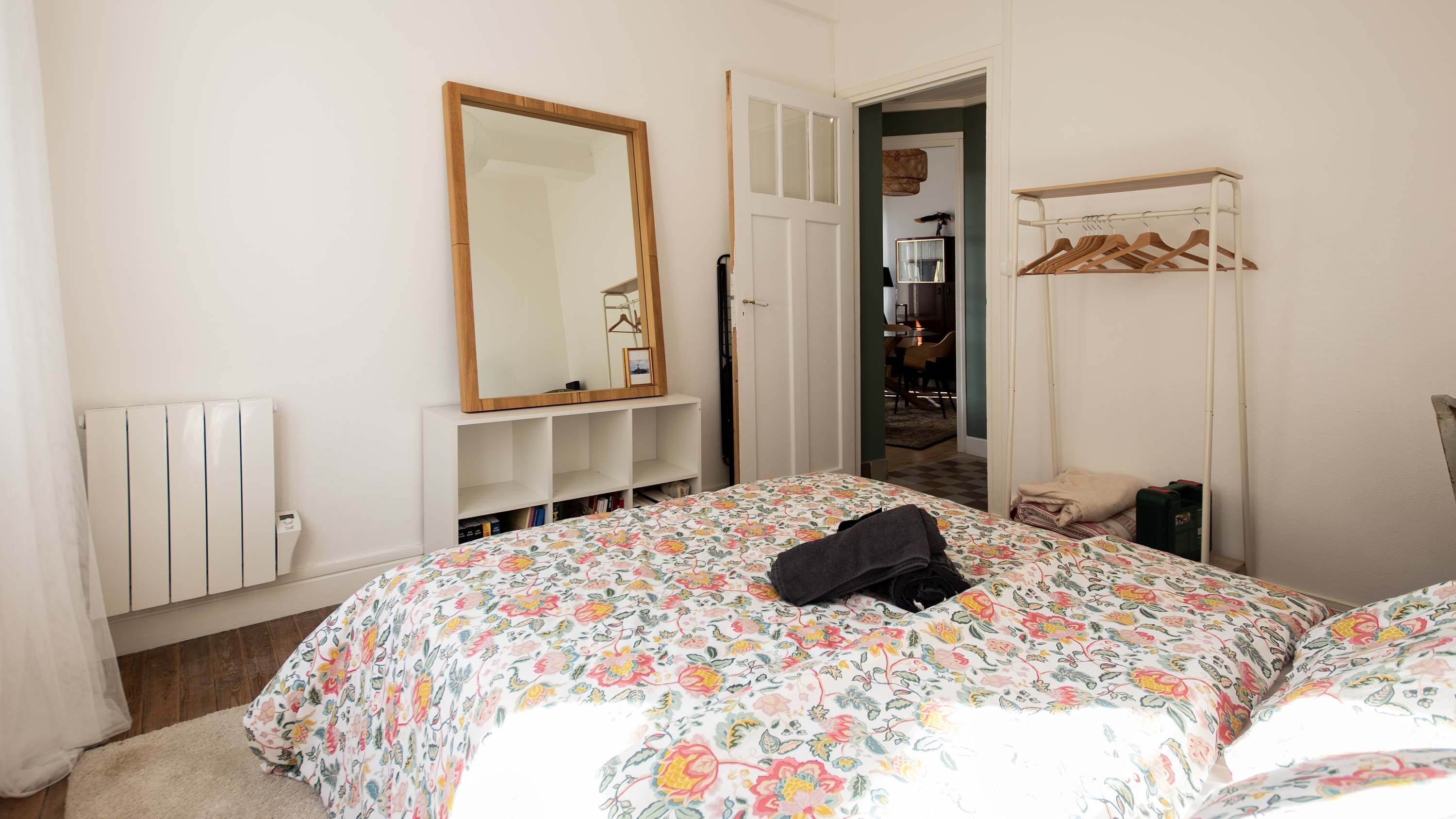 Ein Schlafzimmer mit Bett, Spiegel, Kleiderschrank und Heizkörper.