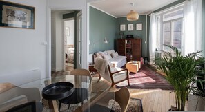 Un salon comprenant un canapé, une table basse, une bibliothèque et une grande fenêtre.