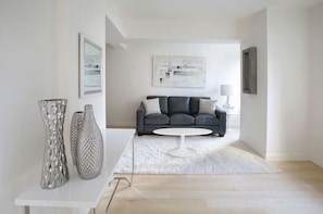 A modern living room with a grey sofa, white coffee table, and abstract artwork on the wall.