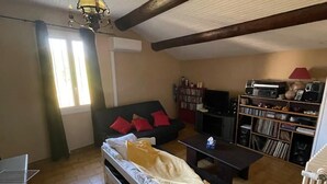 A loft-style room with a bed, a sofa, a coffee table, a bookshelf, and a radiator.