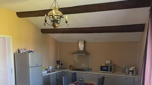 A compact room with a bed, a small dining table with chairs, a kitchenette with a stove, microwave, and refrigerator.