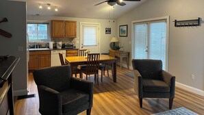 Una cucina moderna con armadietti in legno, un'area pranzo con tavolo e sedie in legno e una ventola a soffitto.