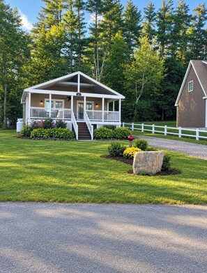 A two-story house with a porch, a stone planter, and a white fence. - 2 bedroom Lake home on Private Road directly across from private community beach (Windham)