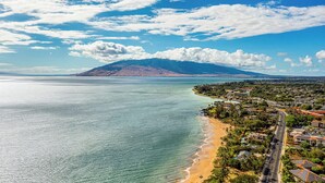 Un pueblo costero con una playa, una montaña al fondo y un cielo despejado.
