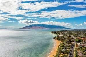 A coastal town with a beach, a mountain in the background, and a clear sky. - New Listing Discount! Beautiful Ground Floor Tropical Oasis with Ocean View! (Kihei)