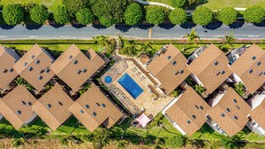 Complejo residencial con varias edificaciones de dos pisos, una piscina central y una calle con señales de 'NO ESTACIONAR'.