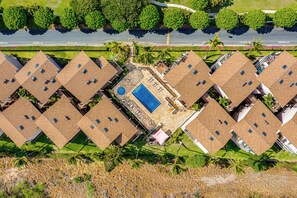 A residential complex with multiple two-story buildings, a central swimming pool, and a road with 'NO PARKING' signs. - New Listing Discount! Beautiful Ground Floor Tropical Oasis with Ocean View! (Kihei)