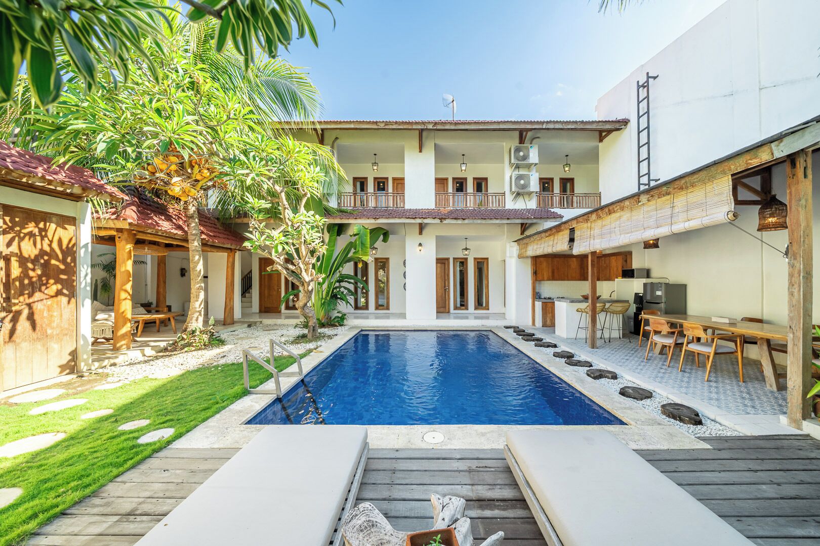 Ein zweistöckiges Haus mit Pool, Sitzgelegenheiten im Freien und einer Küchenzeile.