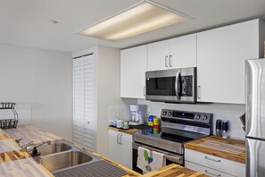A modern kitchen with stainless steel appliances, a wooden countertop, and a white cabinet. - Salt Ponds | Work & Relax in Key West | Poolside Condo • Balcony • Near Beach (Key west)