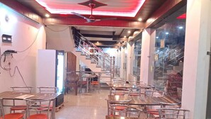 A restaurant with multiple tables and chairs, a staircase, and a ceiling fan.