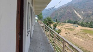 A balcony with a view of terraced fields and mountains.