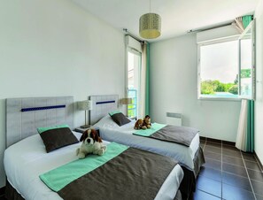 A hotel room with two beds, a window with a view, a hanging lamp, and a stuffed dog on one bed. - Seaside Apartment in Saint-palais-sur-mer (Saint-Palais-sur-Mer)