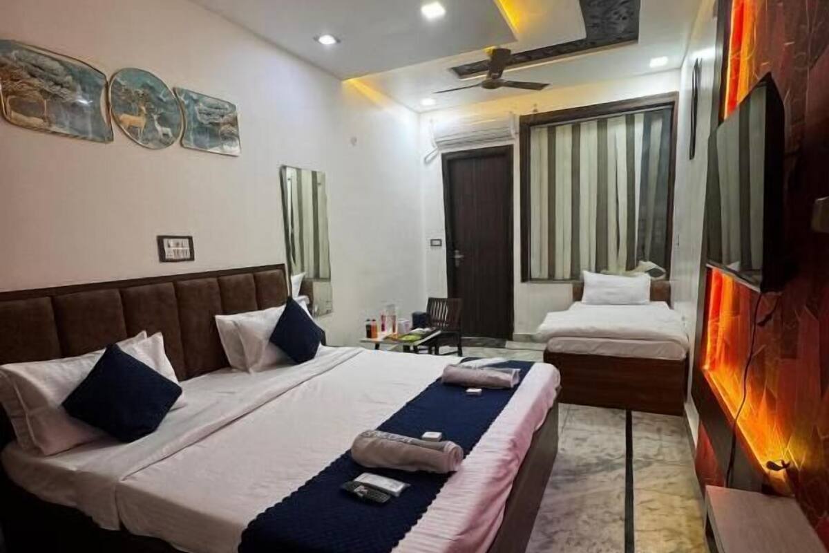 A modern hotel room with a large bed, a ceiling fan, and a wall-mounted TV.