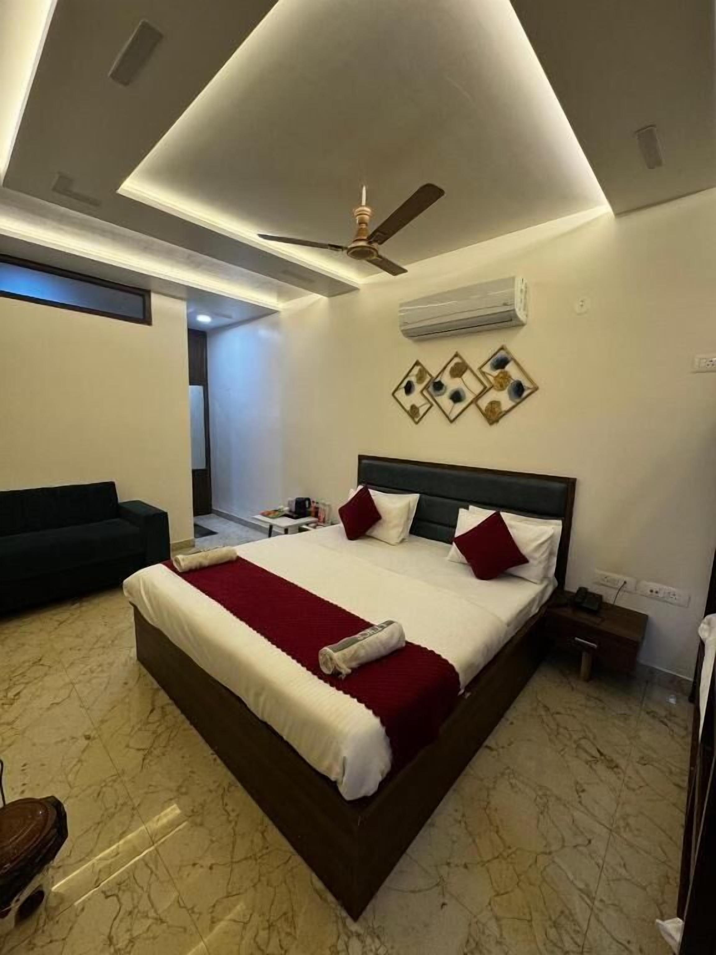 A modern hotel room with a large bed, a ceiling fan, an air conditioning unit, and a nightstand.