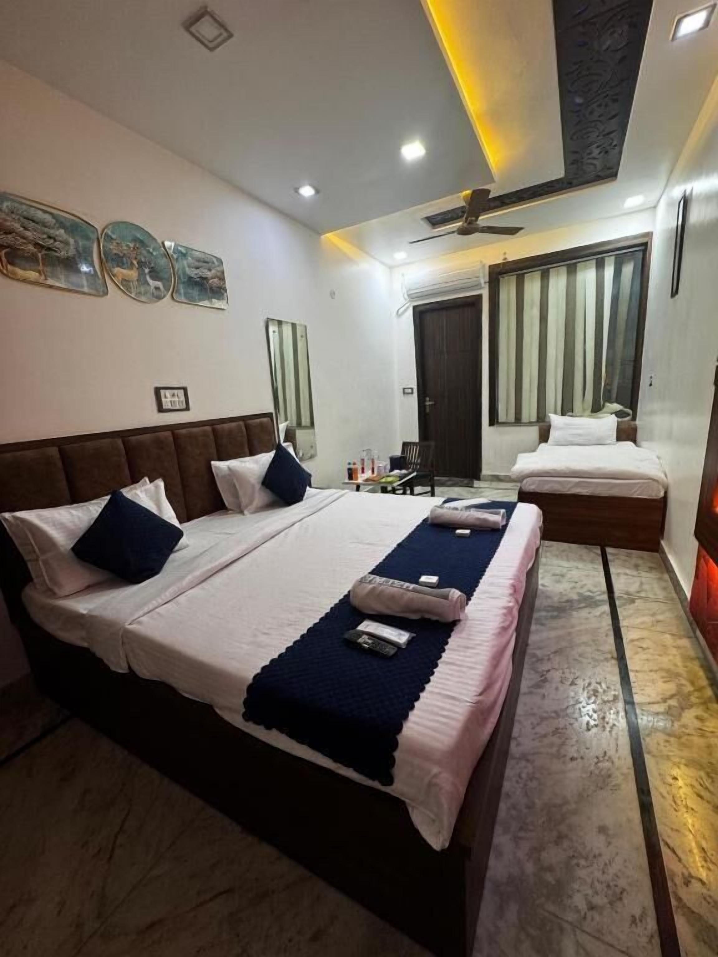 A hotel room with a large bed, a smaller bed, a desk, and a mirror.