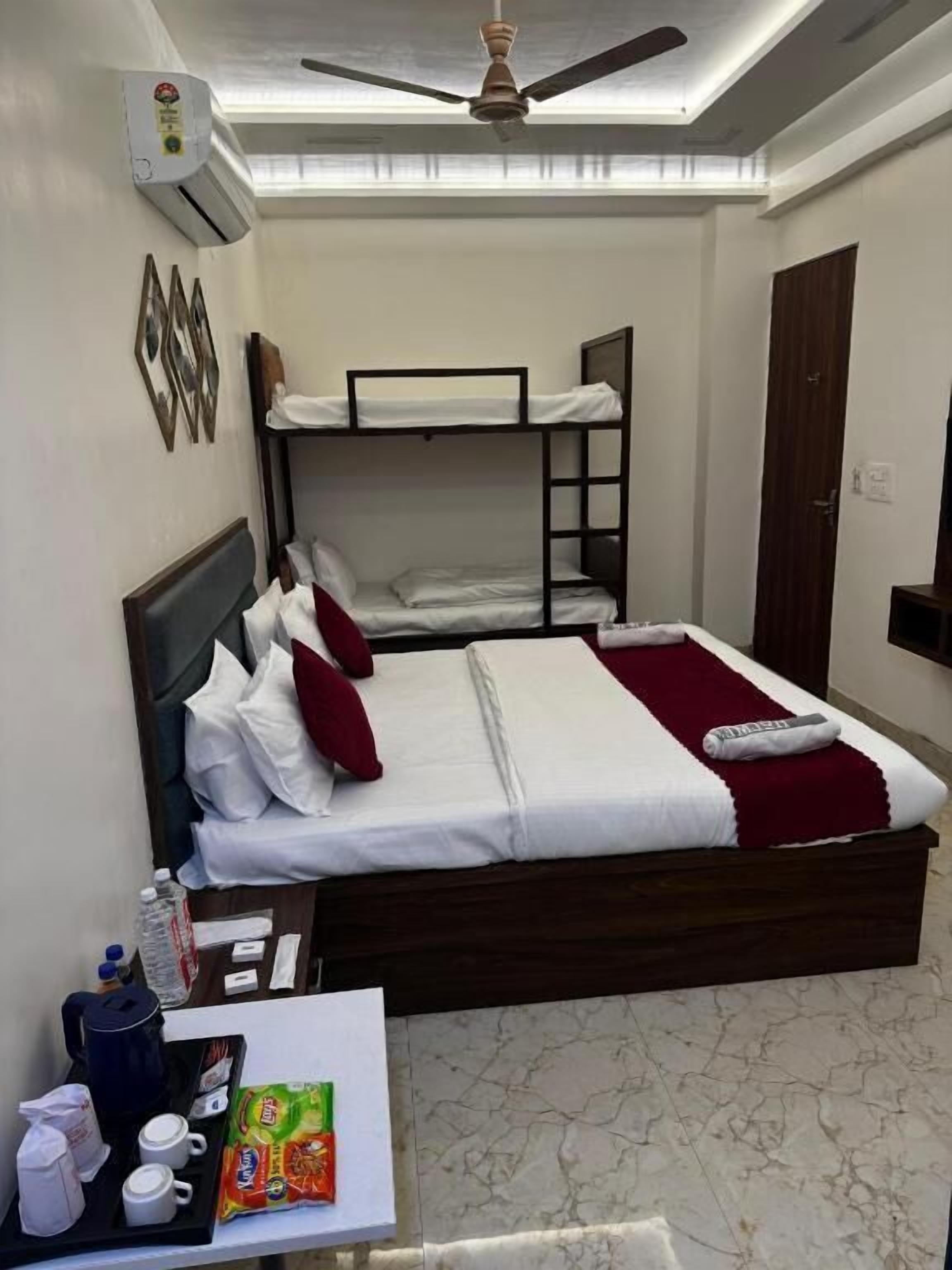 Dormitorio con literas, ventilador de techo, una mesita con una bandeja de desayuno y aire acondicionado instalado en la pared.