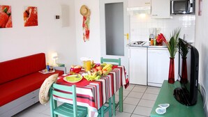 A compact living space with a kitchenette, dining area, and a red sofa. - Spacious Beachside Apartment for 6 (Saint-Cyprien)