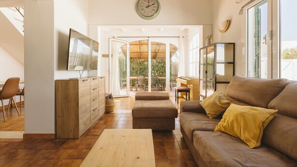 Una sala de estar moderna con sofá, reposapiés, aparador de madera y televisor de pantalla plana.