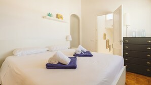 Una habitación de hotel con una cama, un aparador, un espejo y una puerta que da a otra habitación.