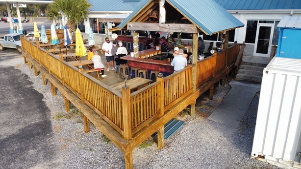 A wooden deck with tables and chairs, a bar area, and a covered seating area. - Reel Em' Inn -3bdr 2.5ba Waterfront Home Located at Pier98 Marina -Pets Welcome (Panama City)