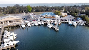 A marina with multiple boats docked, a restaurant with outdoor seating, and a view of the water. - Reel Em' Inn -3bdr 2.5ba Waterfront Home Located at Pier98 Marina -Pets Welcome (Panama City)