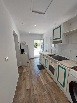 A modern kitchen with a central island, built-in appliances, and a view to the outside. - Small house with swimming pool and parking, in a quiet location close to the beach. (Antibes)